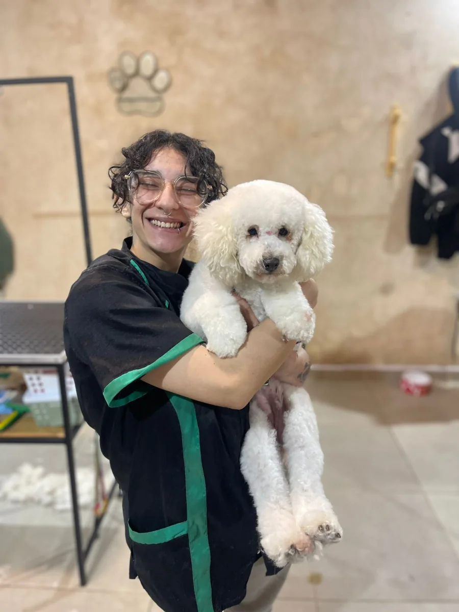 Iara abrazando a un perro blanco después de la peluquería